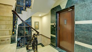 A marble staircase with a wooden door and a framed picture on the wall. - Fabhotel Staywell (Gurugram)