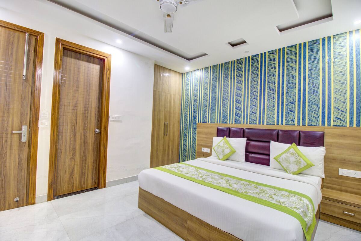 A bedroom with a bed, wooden wardrobe, and a patterned wall.
