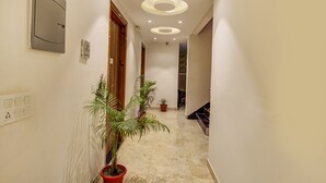 A hallway with potted plants, recessed lighting, and a wooden door. - FabHotel Gross inn Suites (New Delhi)