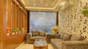 A cozy living room with a sofa, a coffee table, and a decorative wall with a floral pattern. - FabHotel Gross inn Suites (New Delhi)