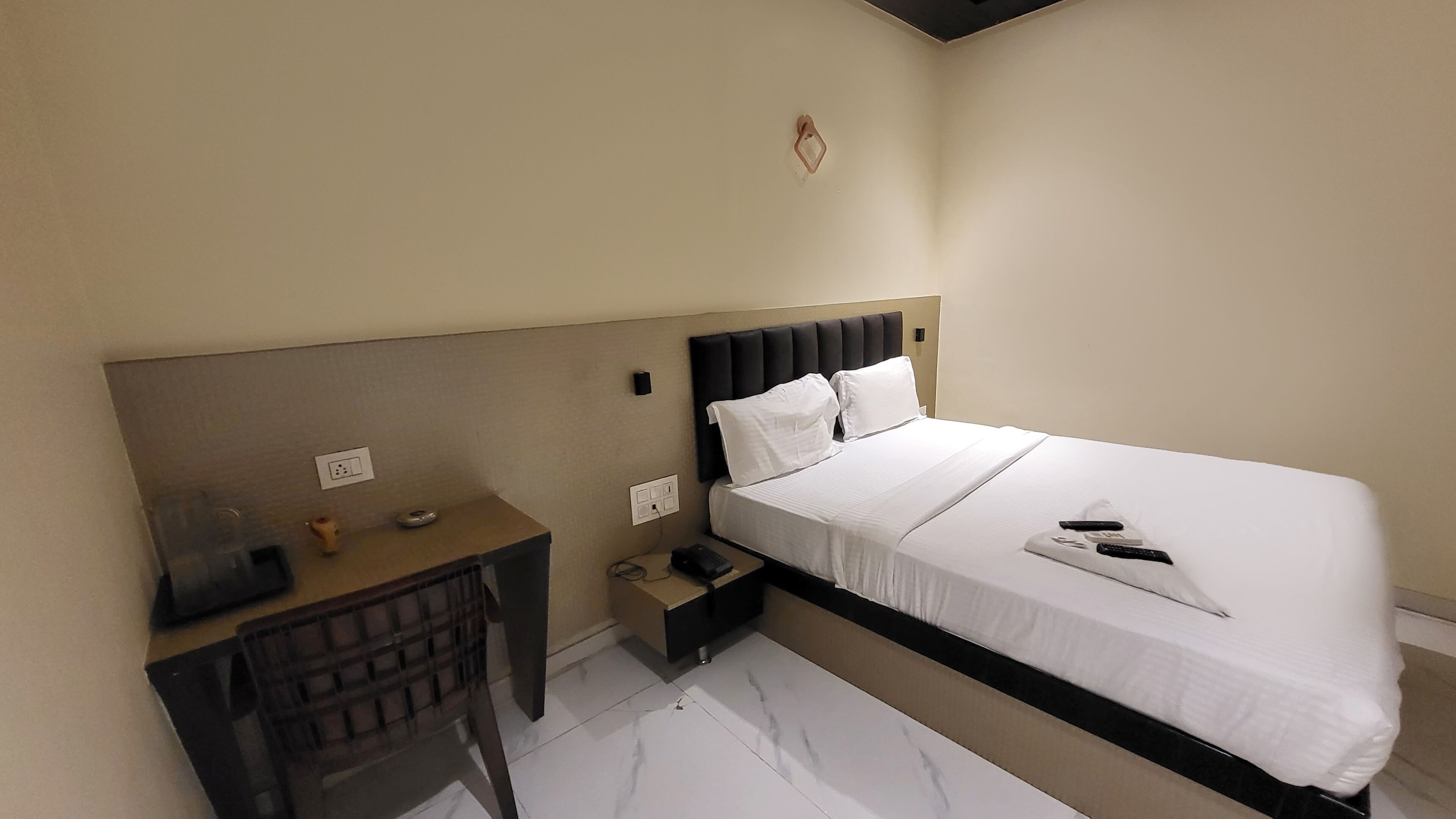 A hotel room with a bed, a desk, and a small table.