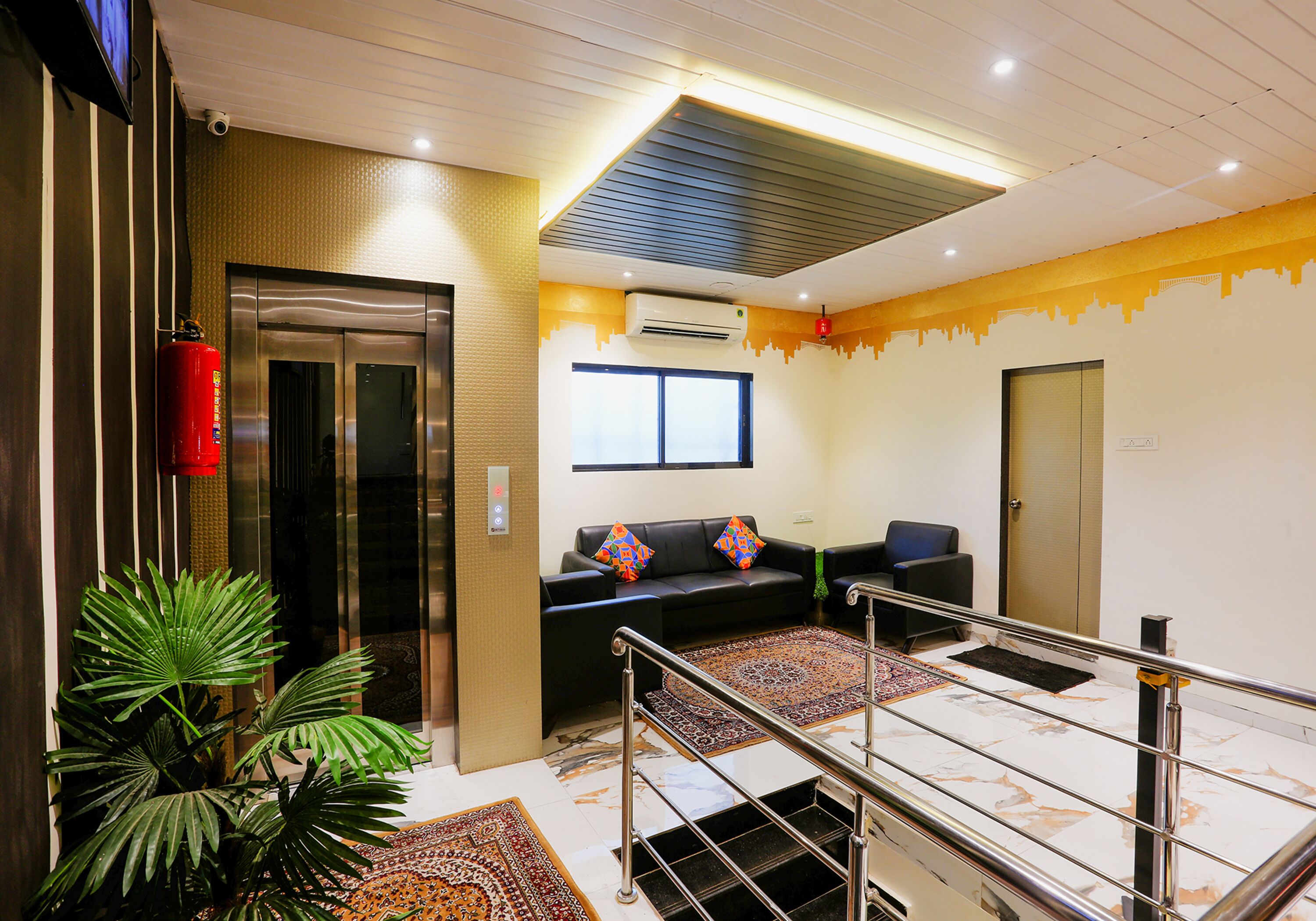 A lobby with a reception desk, a sofa, a staircase, and a fire extinguisher.