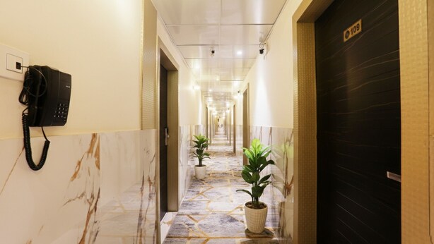 Un pasillo de hotel con piso de mármol, plantas en macetas, un teléfono en la pared y una puerta con el número 109.