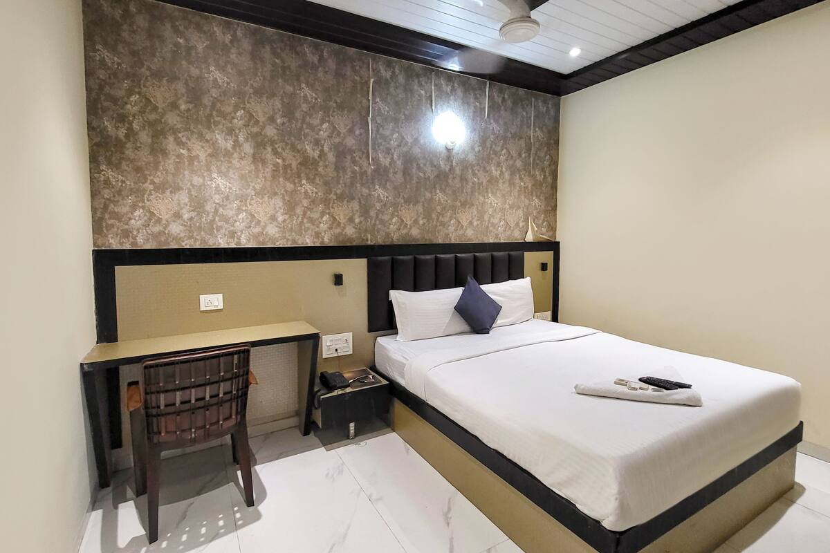 Una habitación de hotel con una cama, un escritorio y una silla.