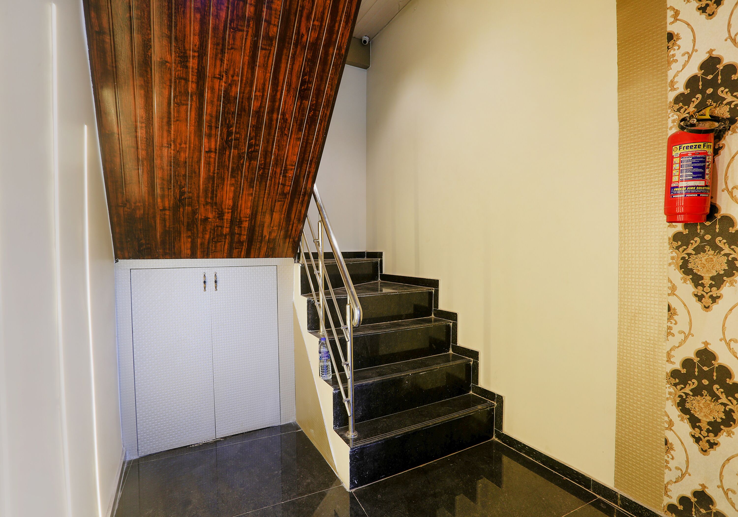 A staircase with black steps, a wooden handrail, and a white door at the bottom.
