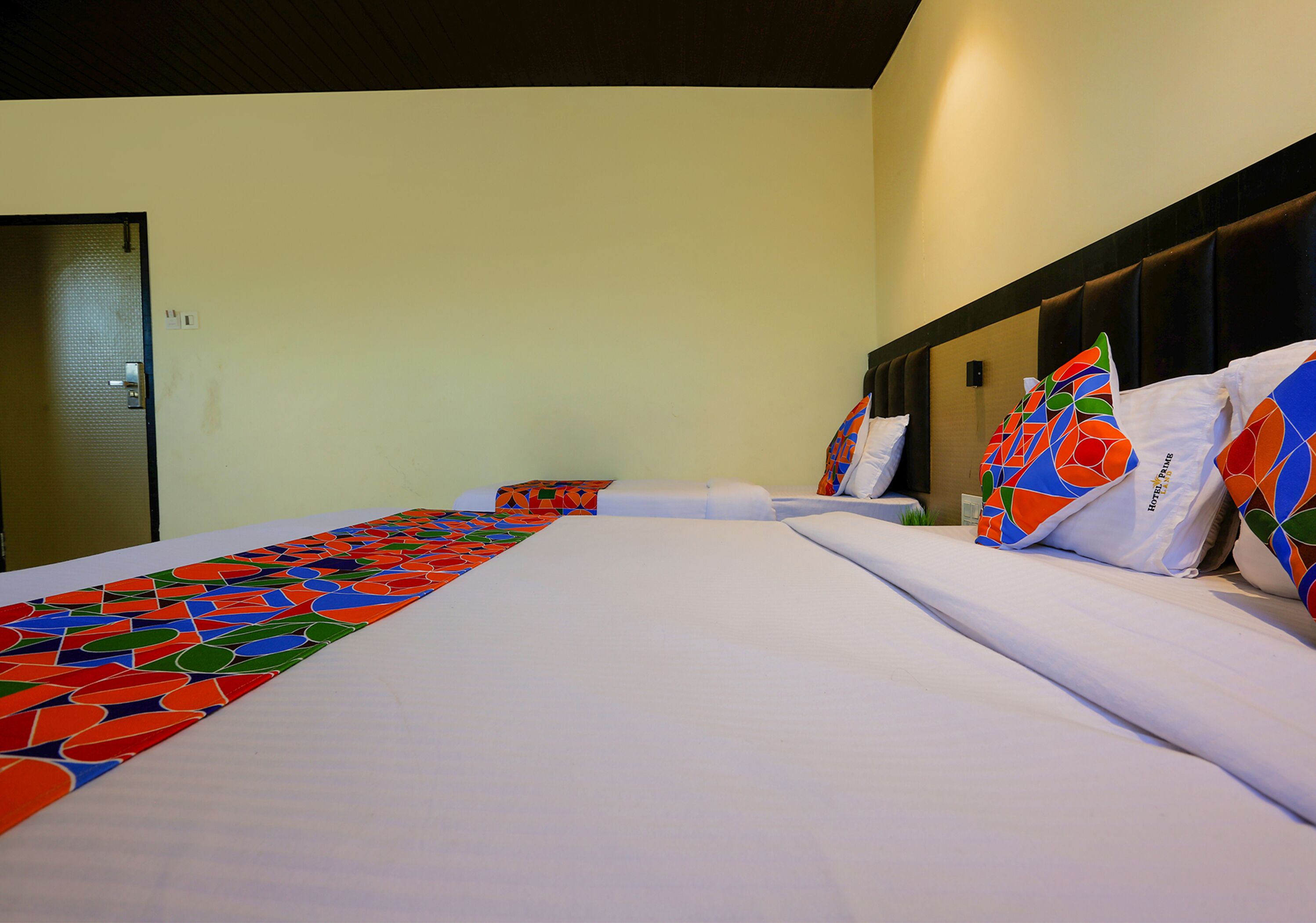 A hotel room with a large bed, a headboard, and a colorful blanket.