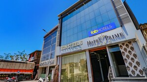 Un hotel con fachada de vidrio moderna, señalización que dice 'Hotel Prime' y 'Sion Steels', y una entrada visible.