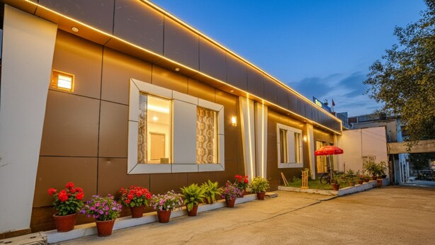 A modern building with a flat roof, large windows, and a series of potted plants along the front. - Fabhotel Grand Inn (Jalandhar)