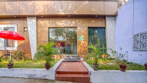 A building entrance with a red umbrella, steps leading up to the door, and potted plants. - Fabhotel Grand Inn (Jalandhar)