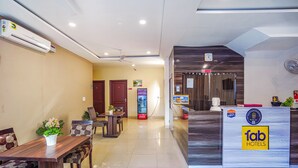 A hotel reception area with a reception desk, seating area, and a Coca-Cola vending machine. - Fabhotel Grand Inn (Jalandhar)