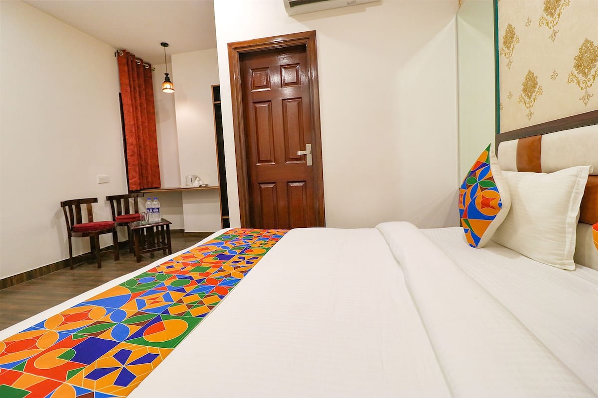 Quarto de hotel com uma cama, uma cadeira, uma mesa e uma porta.