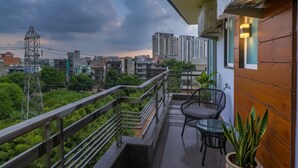 Een balkon met uitzicht op een stadsgezicht, met wolkenkrabbers en een elektriciteitspaal.