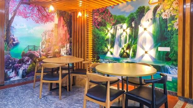 Een restaurant met houten tafels en stoelen, een muurschildering van watervallen en kersenbloesems, en hanglampen.
