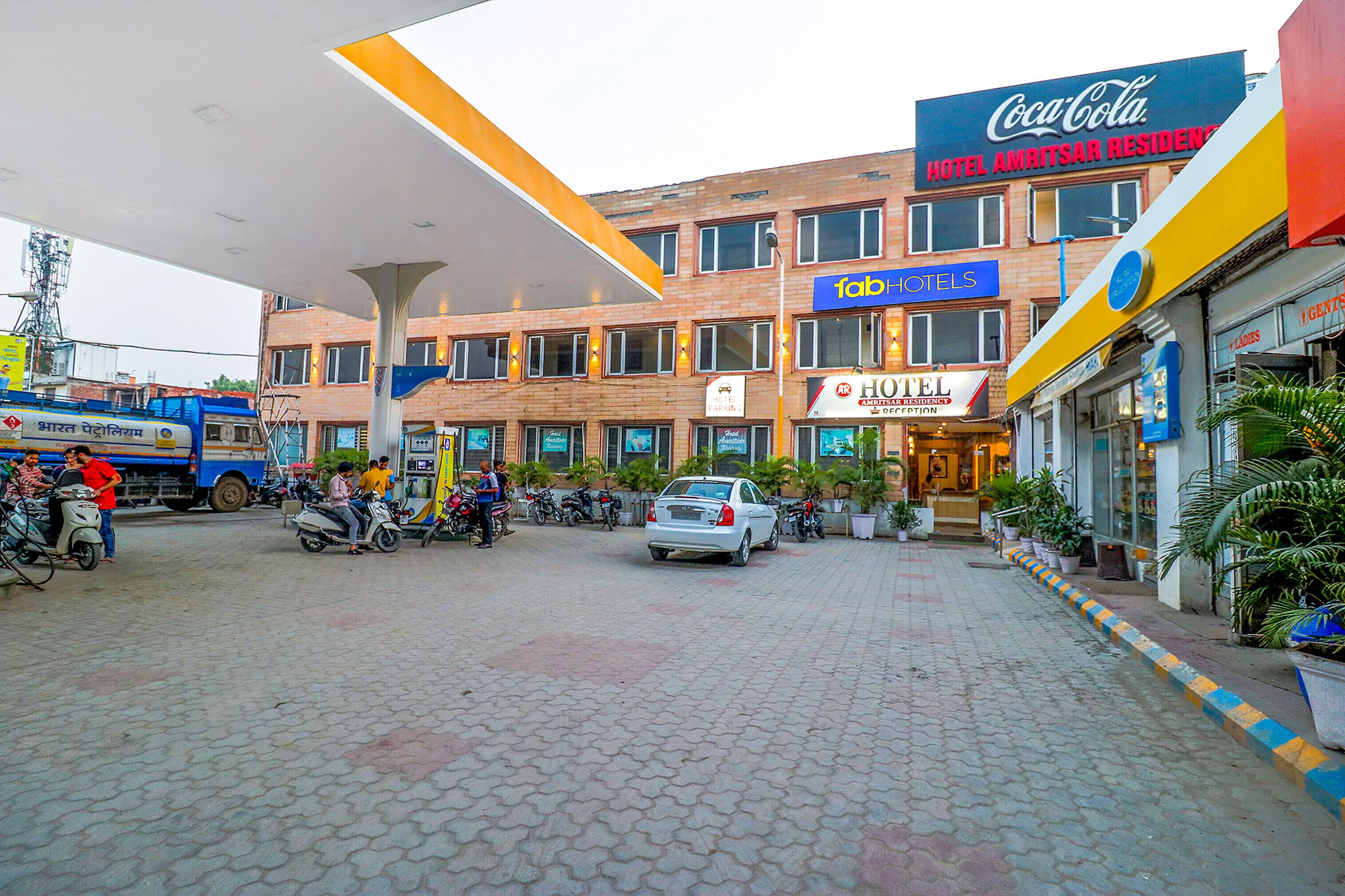 A hotel with a Coca-Cola sign, a tab hotel sign, and a hotel amritsar residence sign.