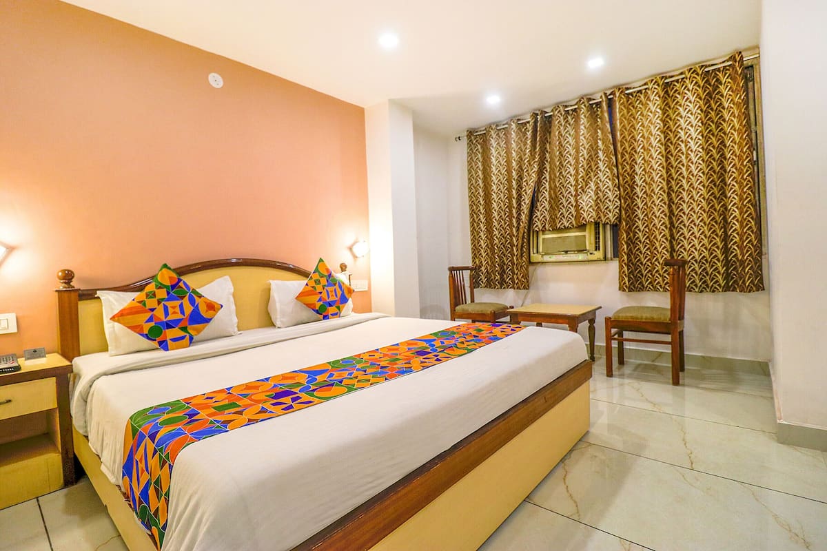 A hotel room with a large bed, a bedside table, a chair, and a desk.
