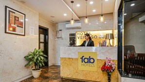 Un mostrador de recepción de hotel con suelo de mármol, una recepcionista y un letrero que dice "fab hotels".