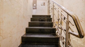Una escalera de mármol con barandales de metal que conduce a una habitación con un cuadro en la pared.