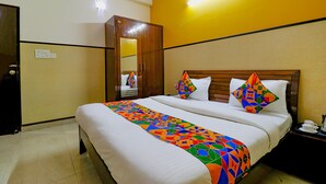 A hotel room with a bed, a wardrobe, a nightstand, and a mirror. - FabHotel Elite Peak (Noida)