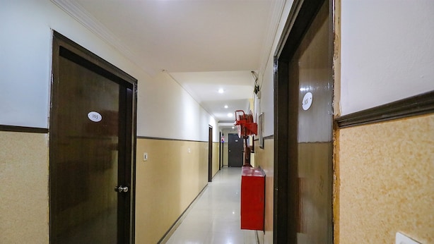 A hotel corridor with doors numbered 103 and 101, a red fire extinguisher, and a light switch on the wall. - FabHotel Elite Peak (Noida)