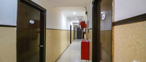 A hotel corridor with doors numbered 103 and 101, a red fire extinguisher, and a light switch on the wall.