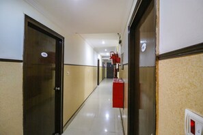 A hotel corridor with doors numbered 103 and 101, a red fire extinguisher, and a light switch on the wall. - FabHotel Elite Peak (Noida)