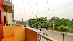 A balcony with a view of a street and trees. - FabHotel Elite Peak (Noida)
