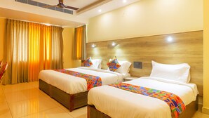 A hotel room with two beds, a ceiling fan, and curtains. - Fabhotel Surya Grand I (Vijayawada)