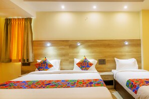 A hotel room with two beds, a wooden headboard, and a colorful bedspread.