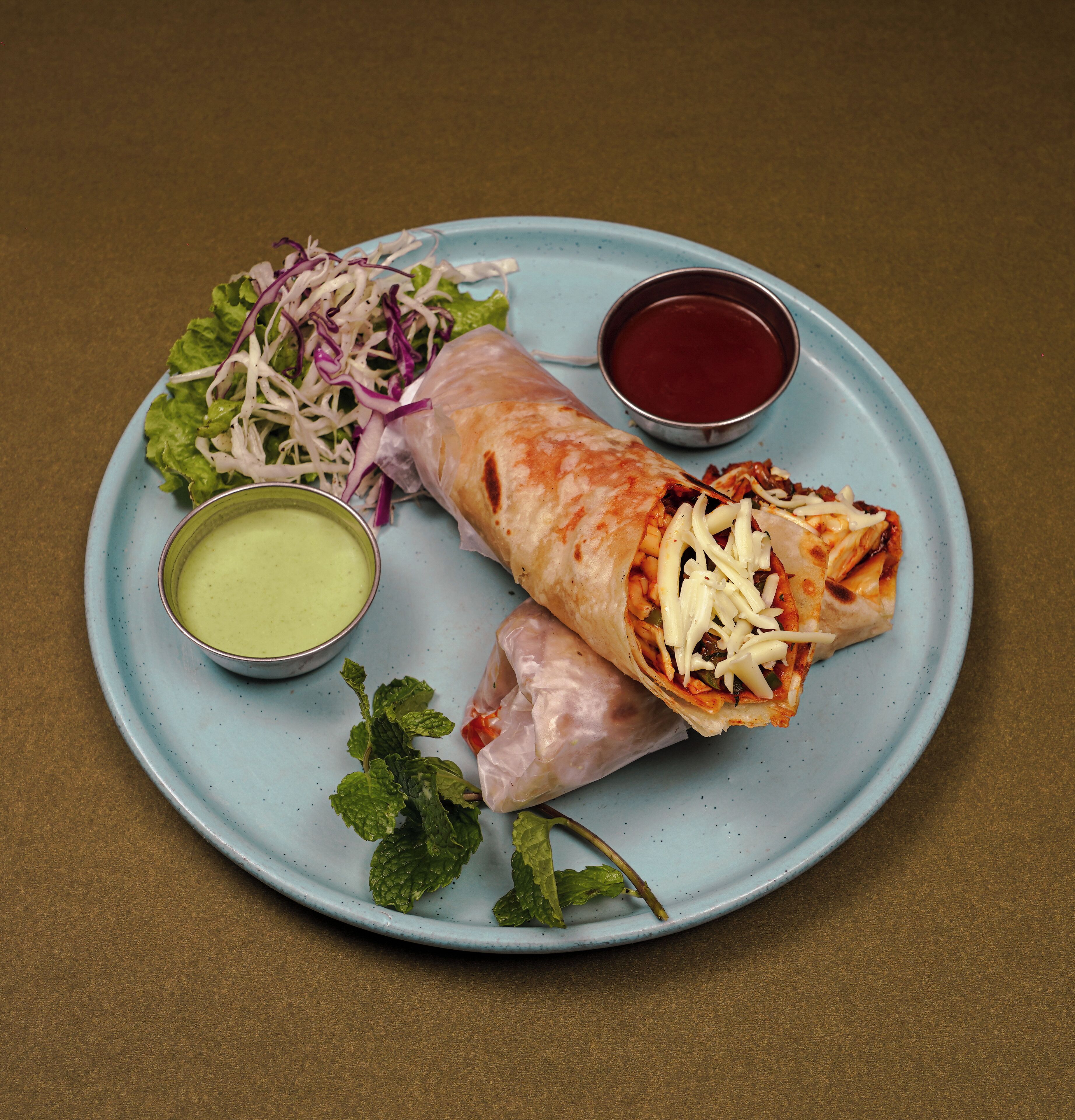 A plate with a wrap, a side salad, and two dipping sauces.