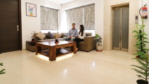 A modern living room with a sofa set, a coffee table, and a potted plant. - FabHotel Oyster Villa - Nr. Paras Hospitals Sushant Lok 1 (Gurugram)
