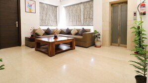 A living room with a sofa, coffee table, and potted plants. - FabHotel Oyster Villa - Nr. Paras Hospitals Sushant Lok 1 (Gurugram)