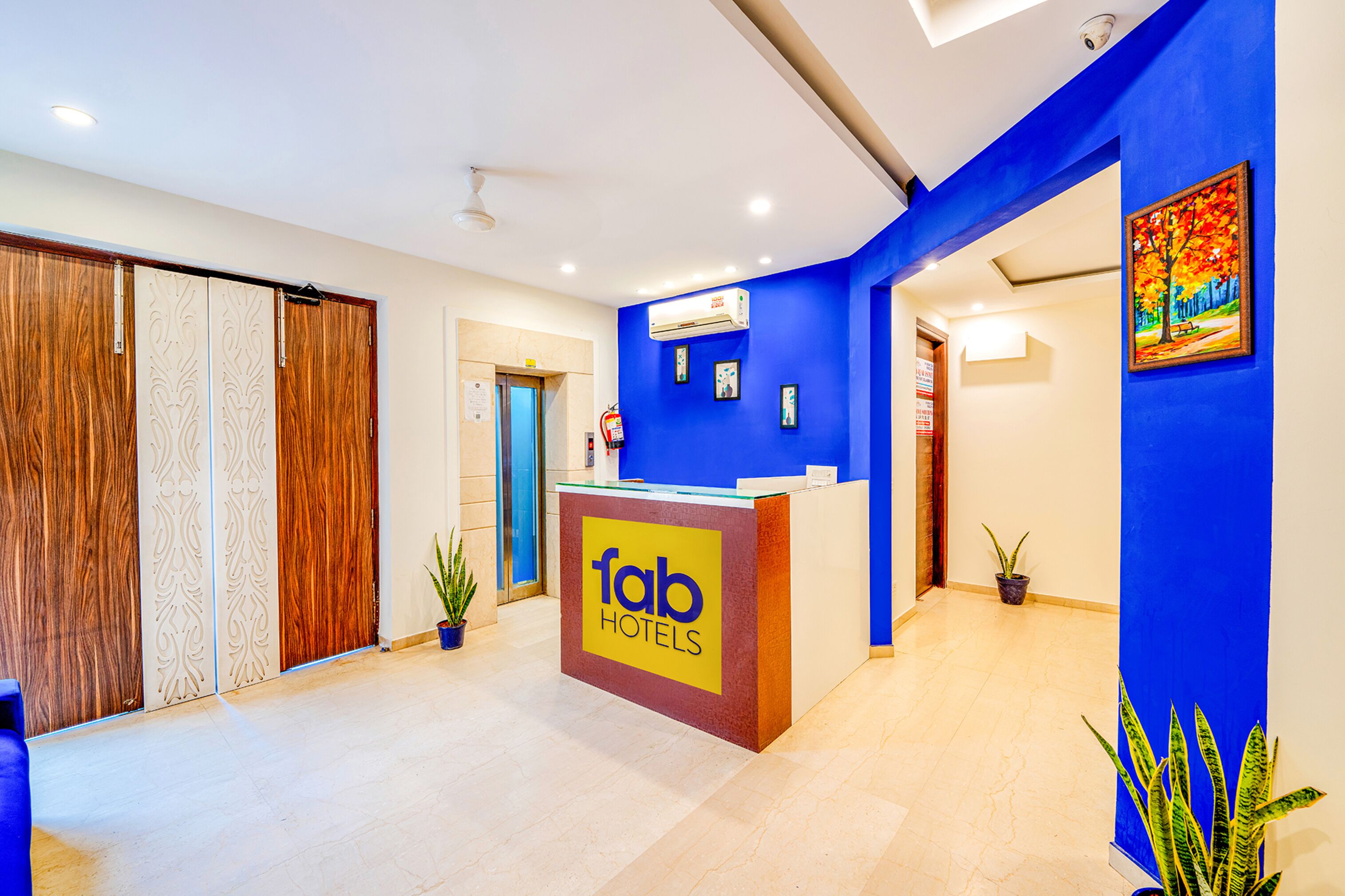 Zona de recepción de un hotel con una pared azul decorativa, mostrador de recepción con la etiqueta 'fab hotels' y un diseño interior moderno.