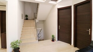 A modern interior with a staircase, wooden doors, and potted plants. - FabHotel Oyster Villa - Nr. Paras Hospitals Sushant Lok 1 (Gurugram)