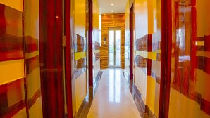 Un pasillo de hotel con paredes espejadas y una puerta central que da a una habitación luminosa.