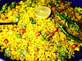 Un plato de arroz amarillo con maní, chiles verdes y una rodaja de limón.
