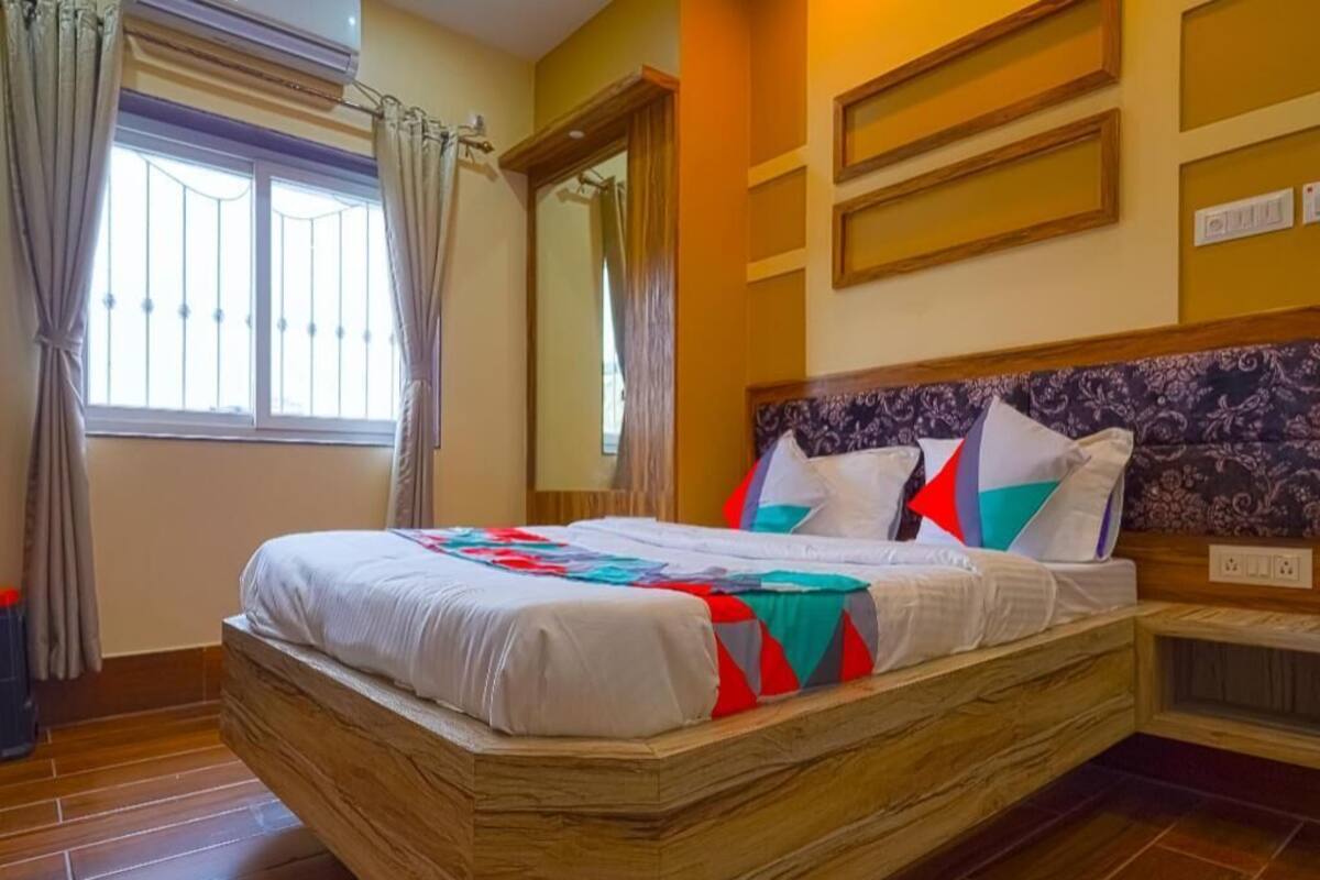 Una cama con un cabecero estampado, una ventana con cortinas y un suelo de baldosas.