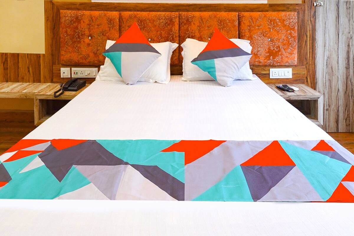 Una habitación de hotel con una cama grande, dos mesitas de noche y un cabecero de madera.