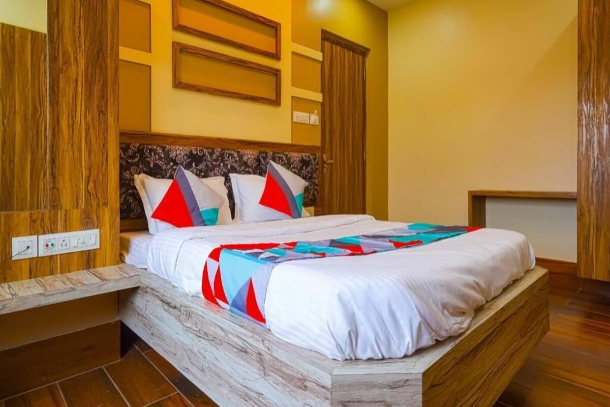 Un dormitorio con estructura de cama de madera, cabecera estampada y colcha.