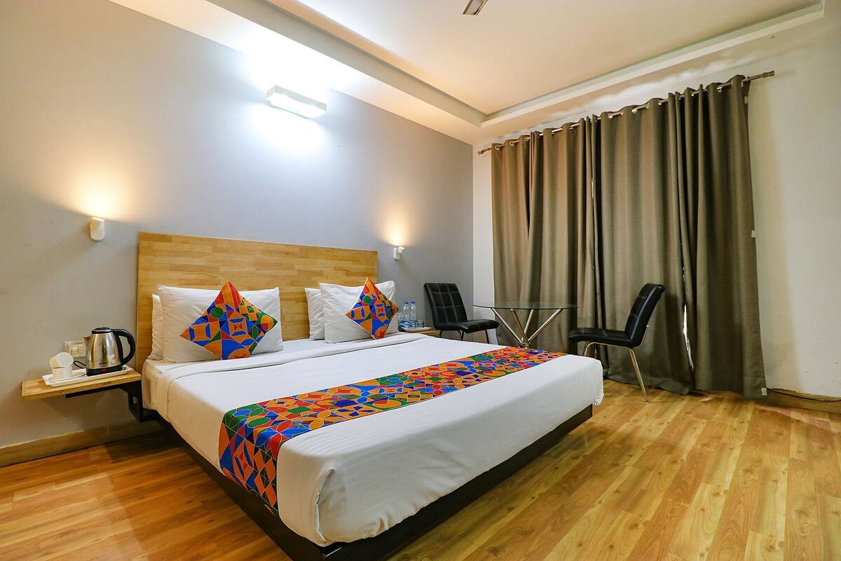 Une chambre d’hôtel comprenant un lit, une table de chevet avec une bouilloire, une chaise et une table avec une bouteille d’eau.