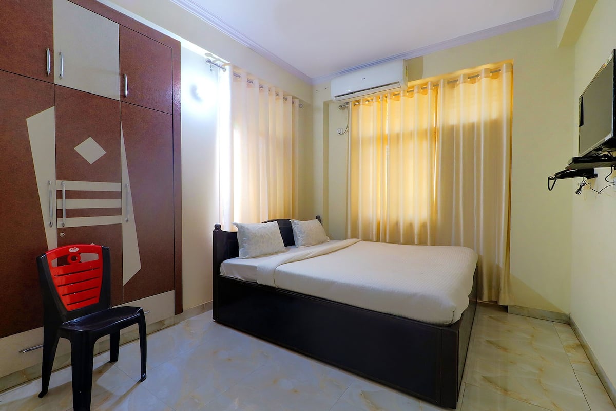 A bedroom with a bed, a chair, a wardrobe, and a TV.