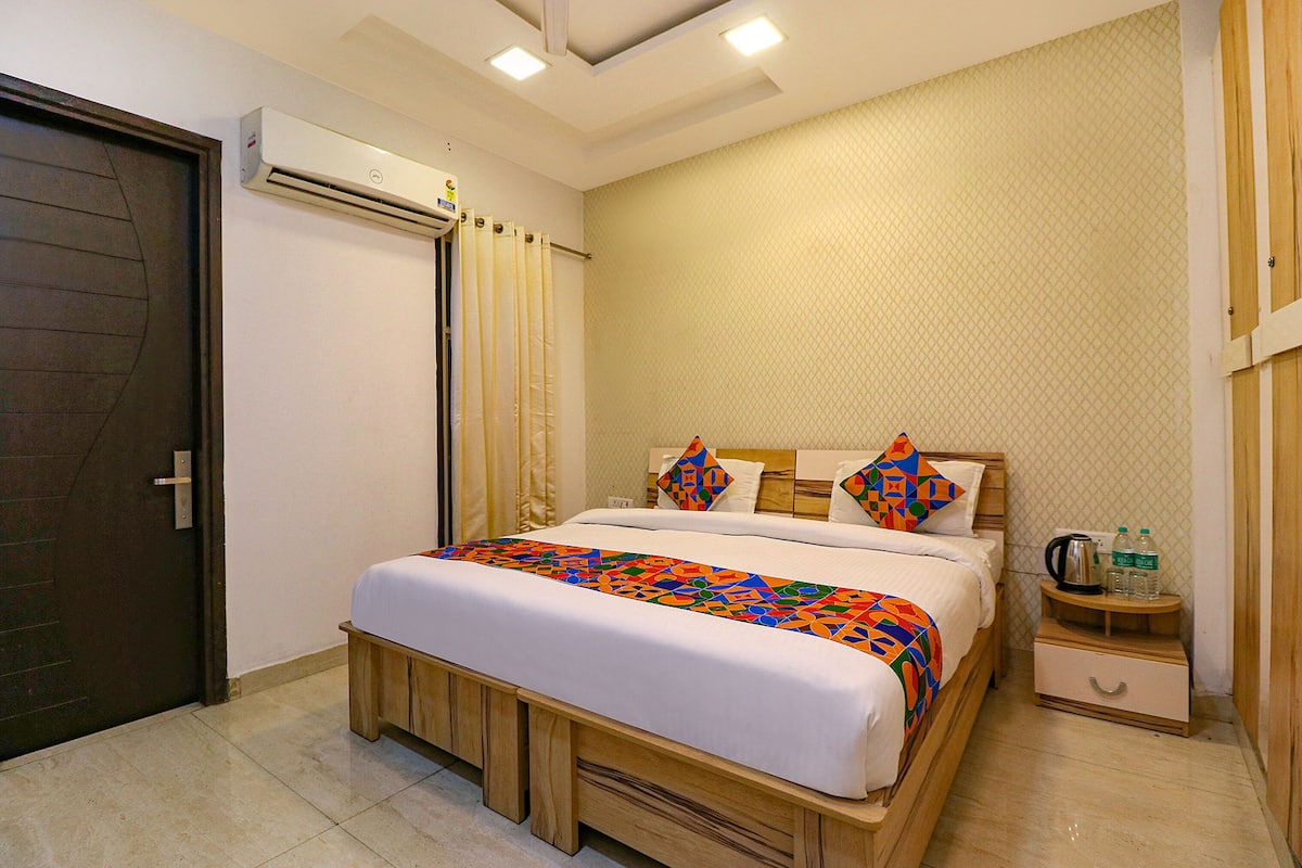 Quarto de hotel bem arrumado com cama, mesa de cabeceira e unidade de ar condicionado.