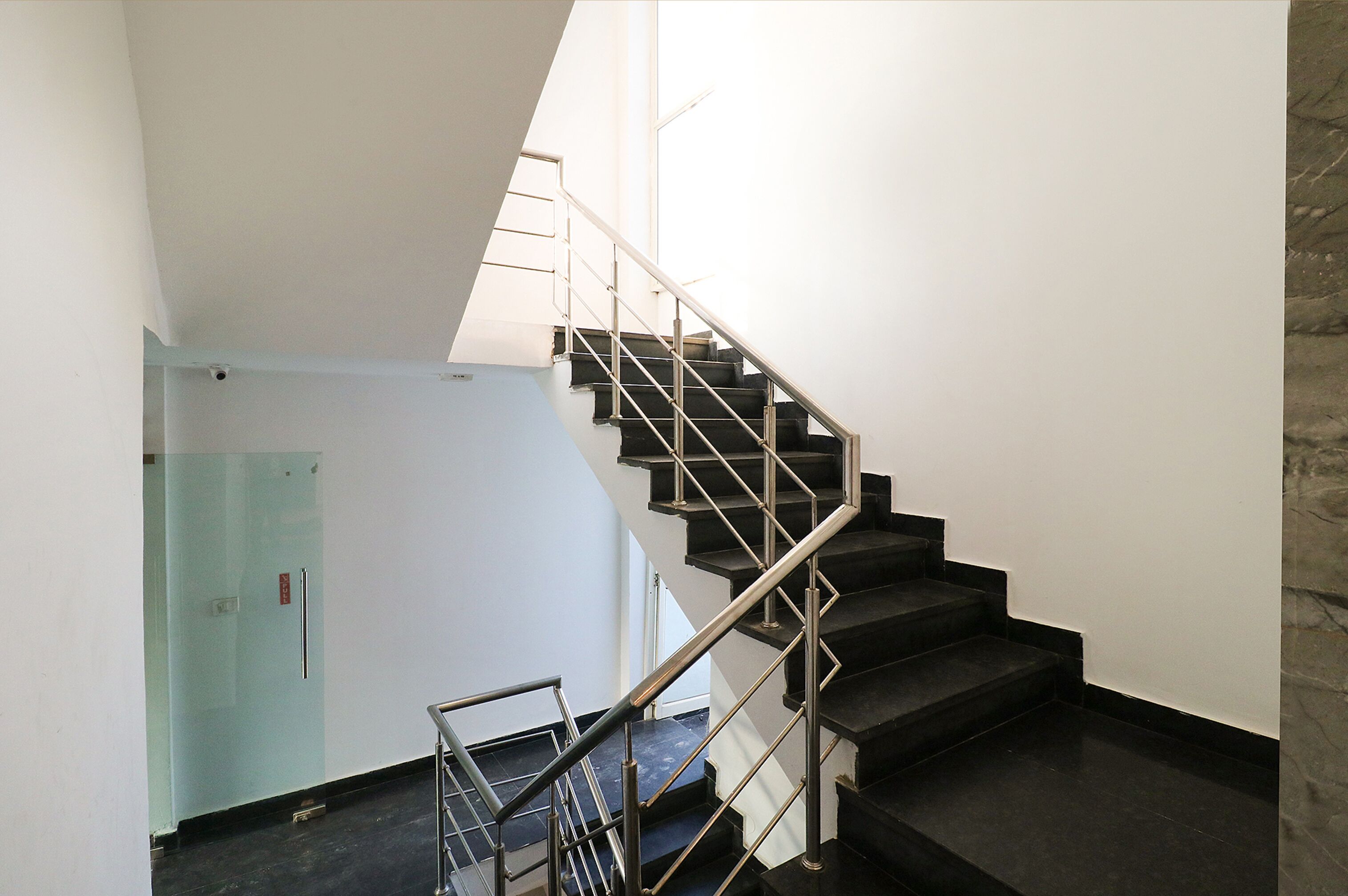 A staircase with metal railings and black steps leading to a landing.