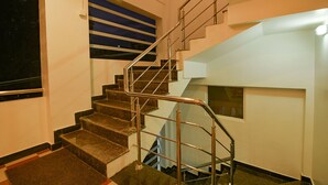 A modern staircase with metal railings and a view of the sky through a window. - FabHotel Greenwood Stays (Ootacamund)