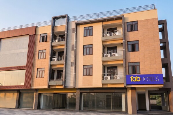 Un edificio de hotel de varios pisos con balcones, ventanas grandes y un cartel que dice 'fabHOTELS'.