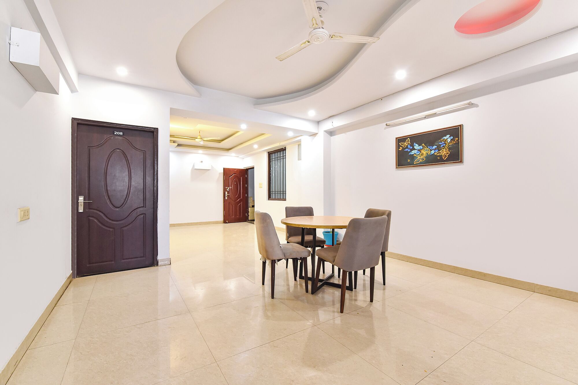 Une pièce comprenant une table à manger, des chaises, un ventilateur de plafond et un tableau accroché au mur.