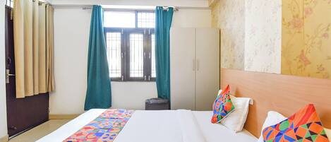 Habitación de hotel con cama, ventana con cortinas, armario y pared con papel tapiz floral.