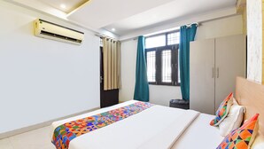Quarto de hotel com cama, guarda-roupa, janela com cortinas e ar condicionado.
