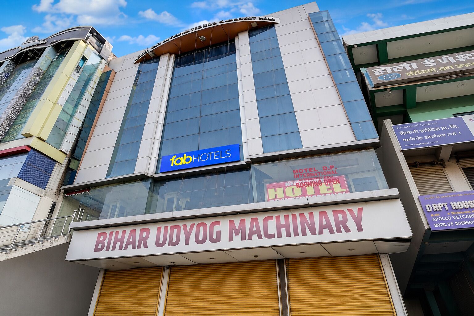 Un edificio con un cartel que indica 'fabHOTELS' y 'Bihar Udyog Machinery' en la planta baja.