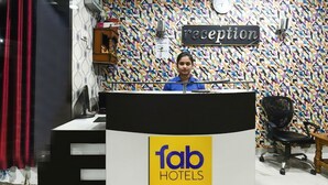 Un comptoir d’accueil orné du logo « fab hotels », d’une enseigne indiquant « réception » et d’un mur à motifs.
