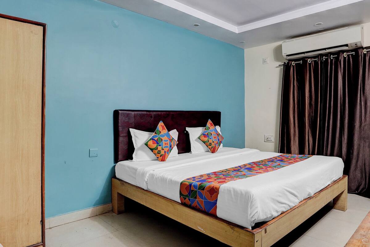 Un dormitorio con estructura de cama de madera, cabecera oscura y pared azul.